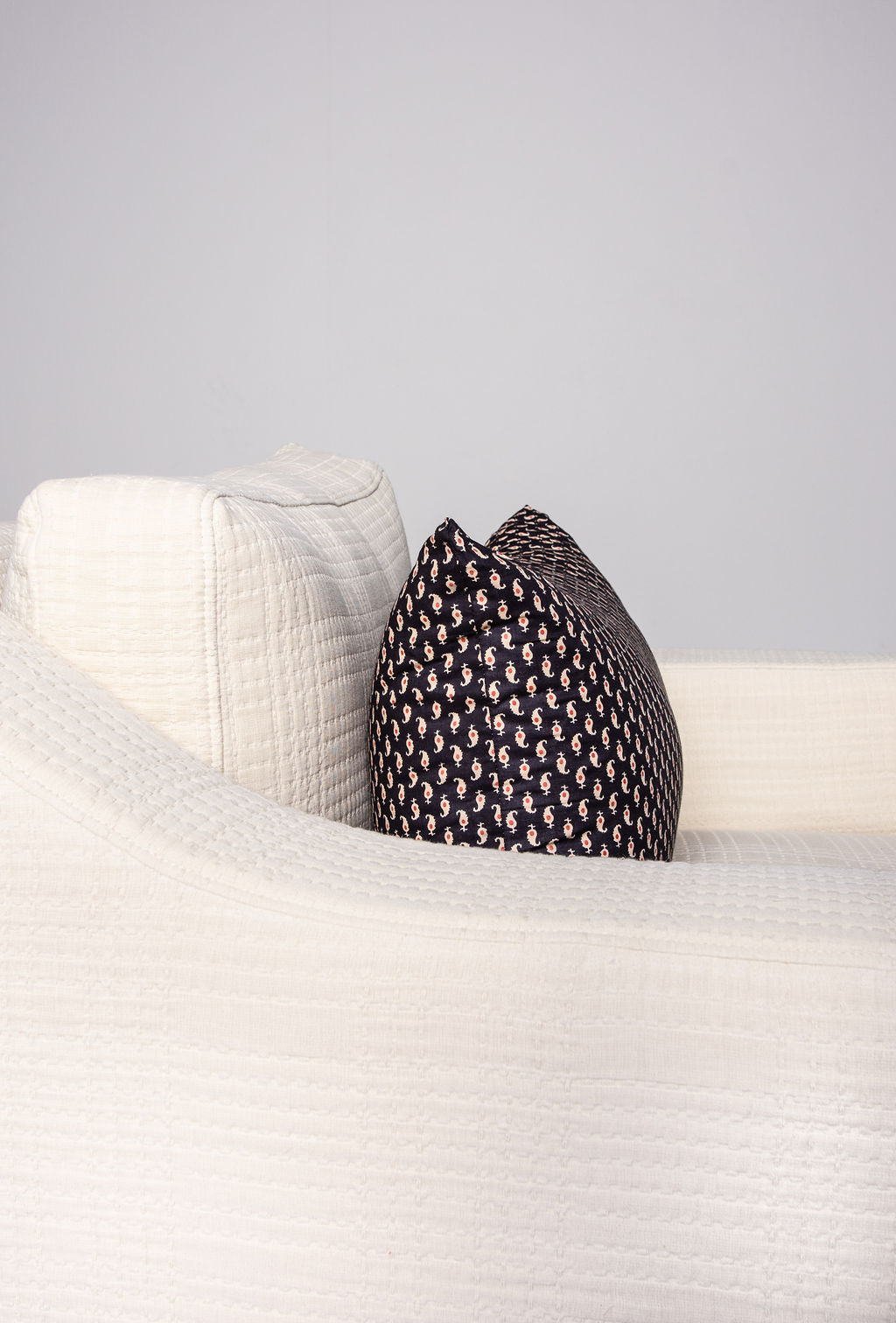 Close up side view with dark pattern pillow of Rue & Williams Home cream-colored custom club chair with matching lumbar pillow, showcasing timeless elegance and comfort. Handcrafted with premium materials, this customizable piece is perfect for elevating any living space. Personalize your comfort with optional fill upgrades. Shop now at Rue & Williams Home.