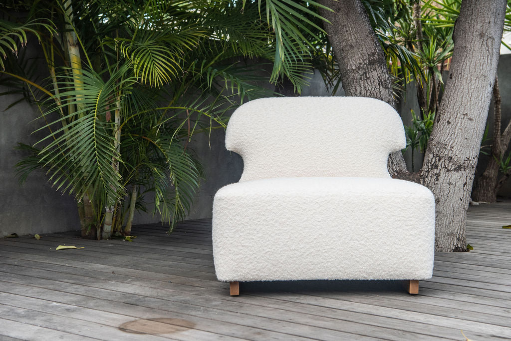 Rue and Williams white boucle meditation chair sitting outside in front of palm trees
